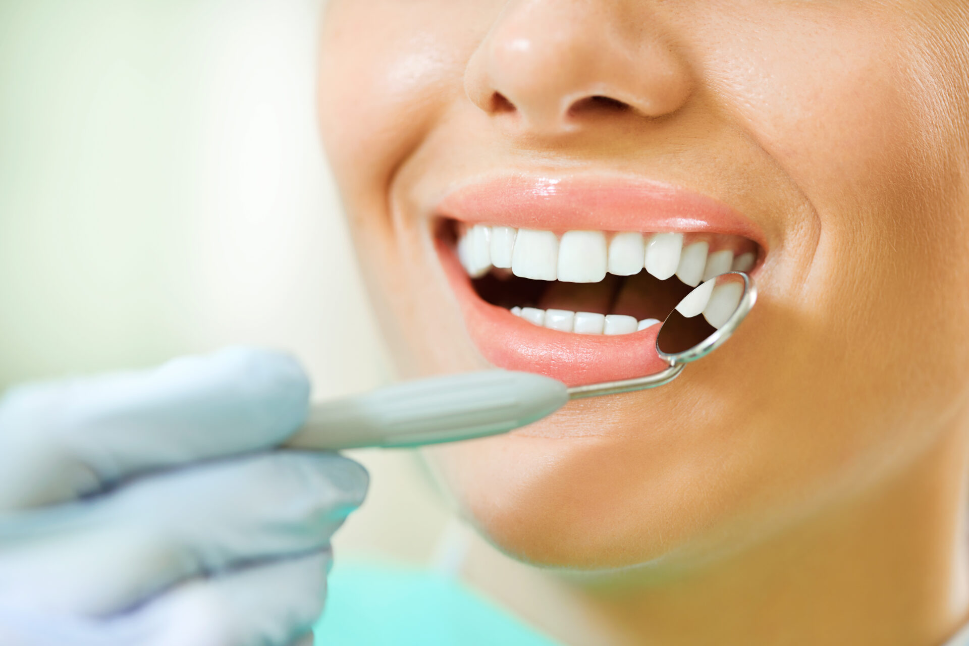 Woman teeth and a dentist mouth mirror close up.