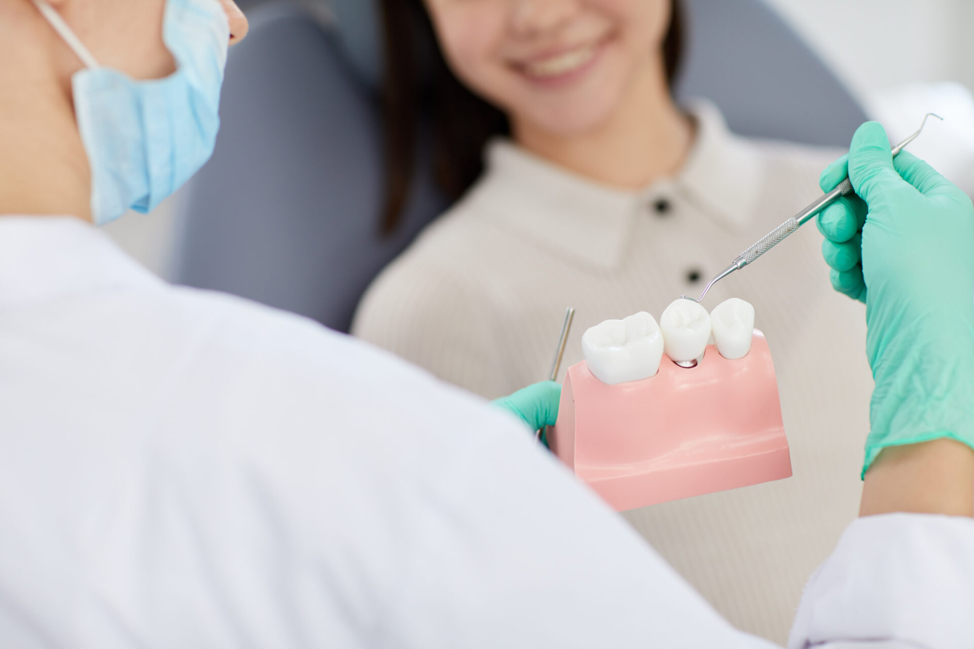 Closeup of unrecognizable dentist holding tooth model while consulting patient in clinic, copy space